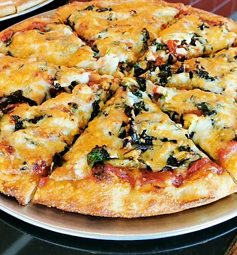 Close view of a spinach and cheese pizza fresh from the oven