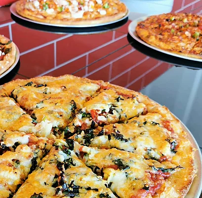 Fresh pizzas on pans along the red-tiled counter