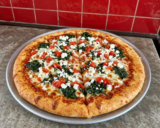 Greek Popeye pizza with spinach, onions, feta and diced tomatoes on a pizza pan
